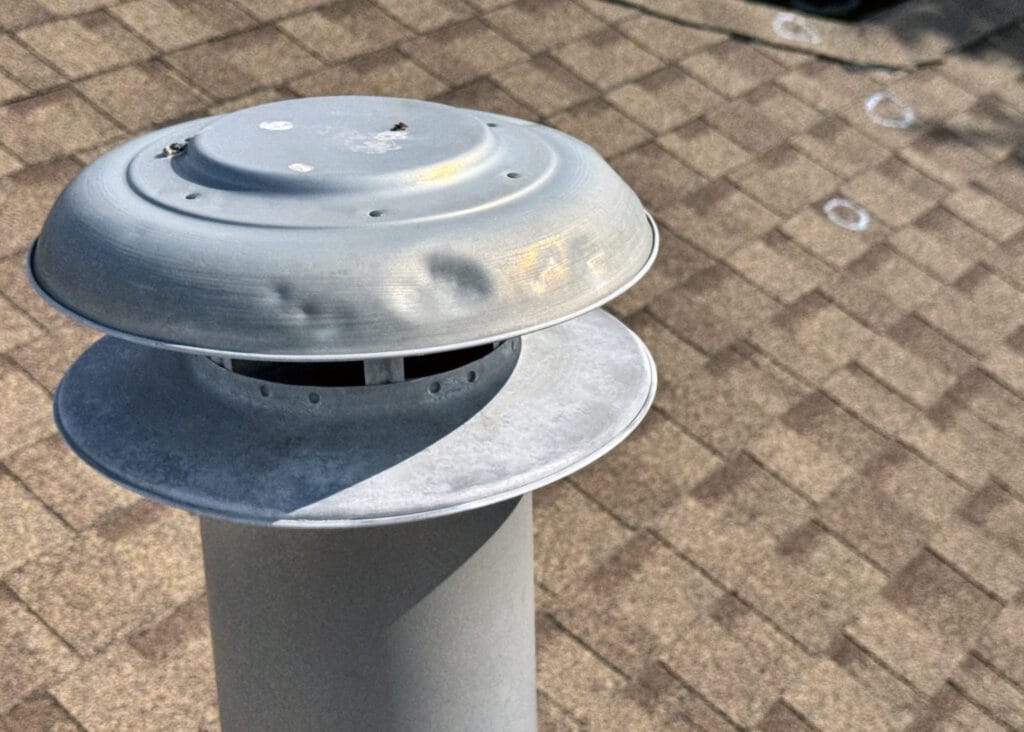 Roof vent cap showing visible hail dents on metal surface